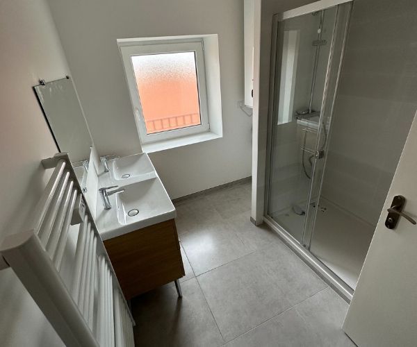 Salle de bain rénovée avec douche et WC dans un appartement d’un immeuble intramuros